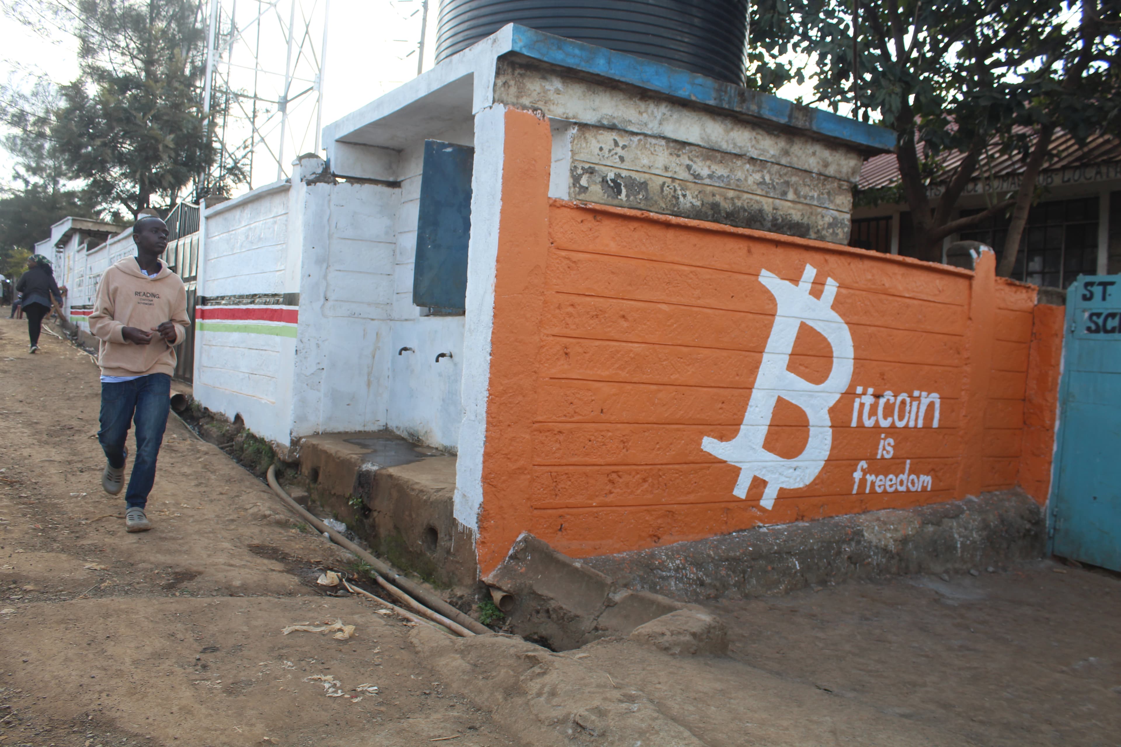White wall in Soweto West painted with Tando, Bitcoin Beach, and Bitcoin Ekasi logos with a 6 West marker